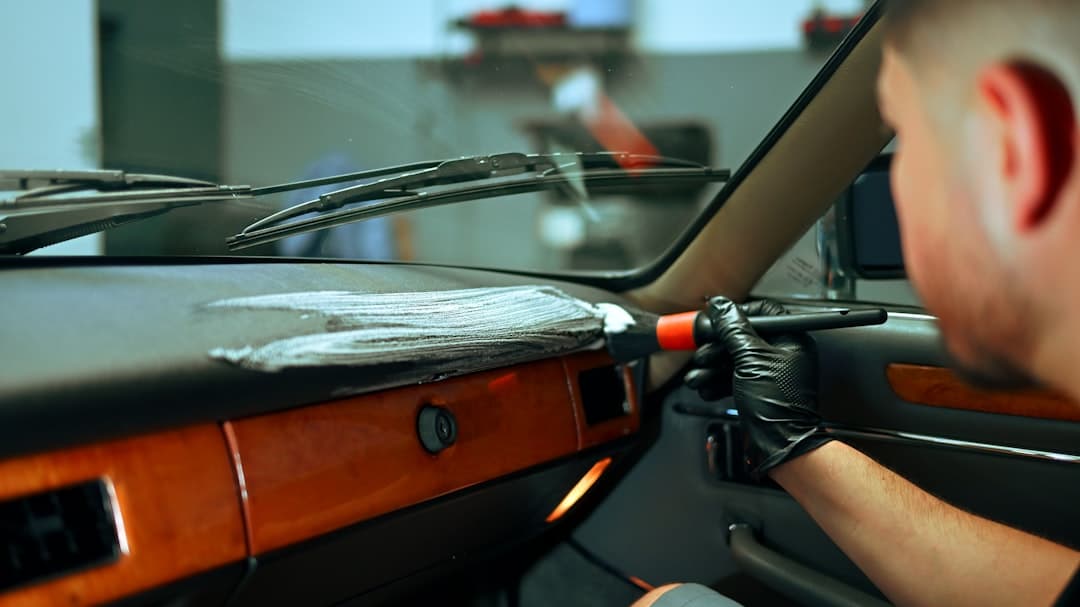 A detailer cleaning a car dashboard with a brush