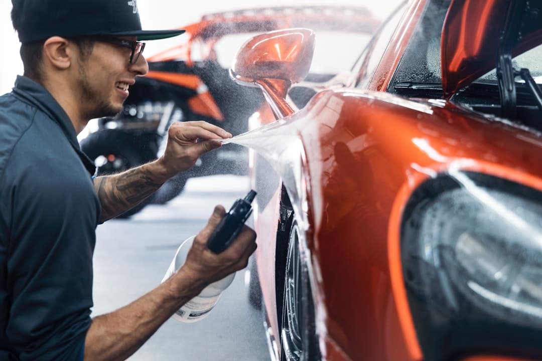 A detailer applying a protective film to a car panel