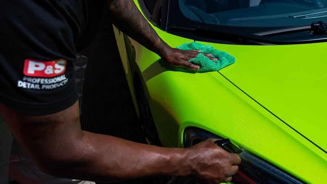 A detailer polishing the side of a car by hand